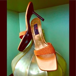 Woman orange heels beaded w/ black bottomed shoe.